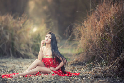 Woman in red dress sitting on field