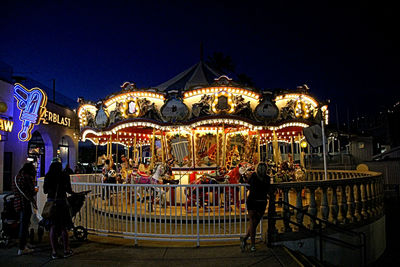 People in illuminated amusement park at night