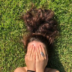 Woman covering face while lying on field