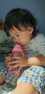 Cute baby girl drinking water while sitting at home