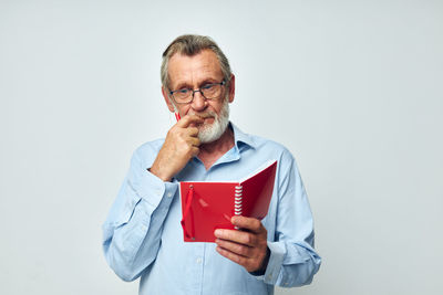 Senior man reading book against white background