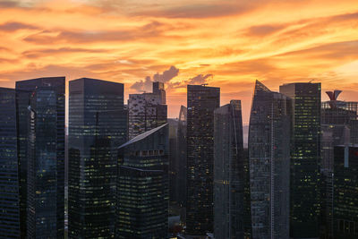 Modern buildings in city against orange sky