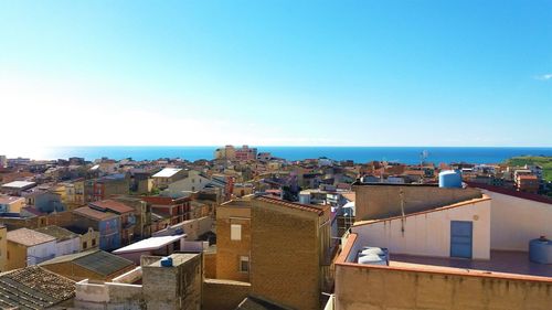 High angle view of townscape by sea against clear sky