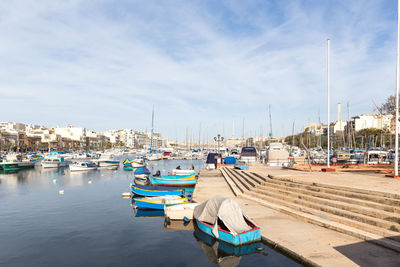 Boats moored at harbor against sky