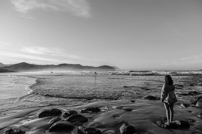 Rear view full length of woman standing at beach against sky