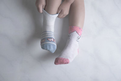 Low section of girl wearing different socks against marble floor