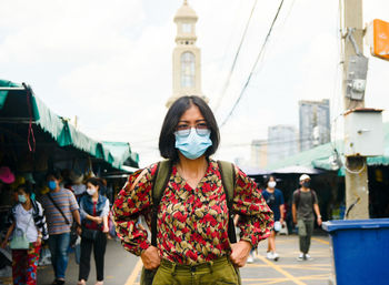 Young woman wearing mask standing on street in city