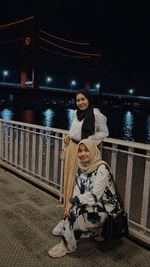 Women near railing in city at night