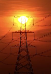 Low angle view of silhouette electricity pylon against sky during sunset