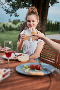 Family making toast during summer picnic outdoor dinner in a home garden