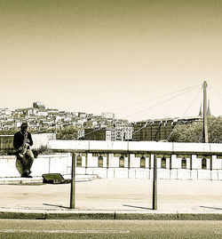 People on bridge against sky in city