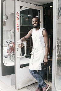 Portrait of happy shop owner standing at doorway