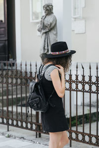 Rear view of woman standing by railing against building