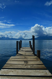 Wooden pier over sea against blue sky