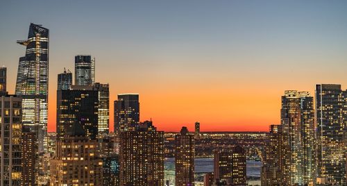 Illuminated buildings in city against sky during sunset