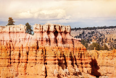 Rock formations on landscape against cloudy sky