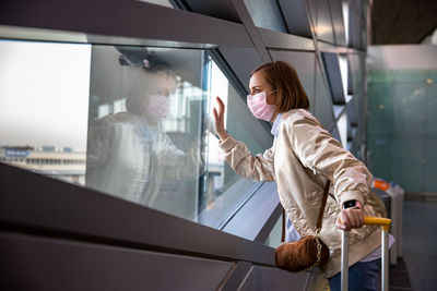 Side view of woman looking through window