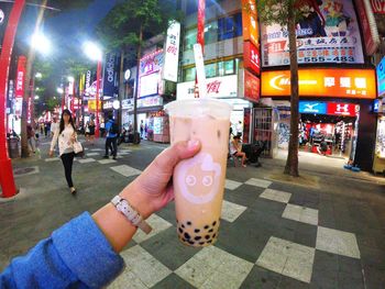 Woman holding ice cream on street in city at night