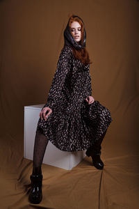 Young woman sitting on seat over fabric