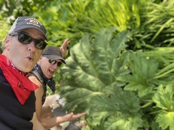 Midsection of woman with sunglasses standing by plants