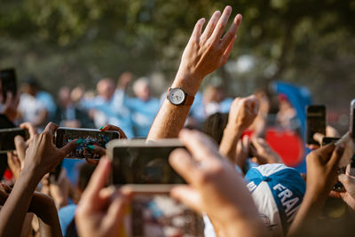 Cropped hands of crowd photographing through mobile phones