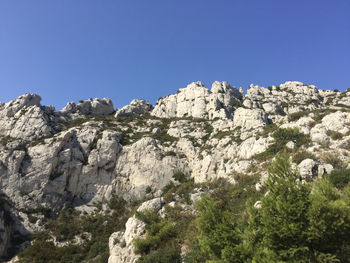 Low angle view of rocks against clear blue sky