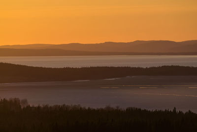 Scenic view of lake and forest against clear sky during sunset