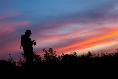 Silhouette man standing on field against sky during sunset