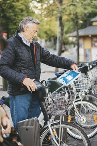 Senior man taking rental bike at parking lot