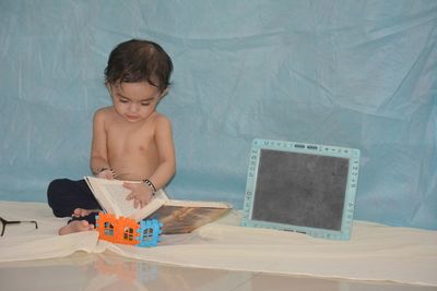 Full length of shirtless boy sitting on paper