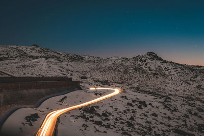 Scenic view of snowcapped mountains against clear blue sky at night