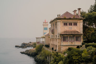 Buildings by sea against sky
