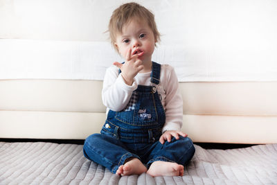 Portrait of cute toddler boy sitting on bed at home