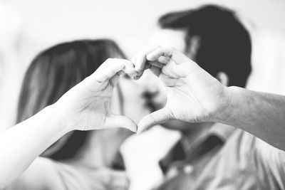 Couple making heart shape while kissing