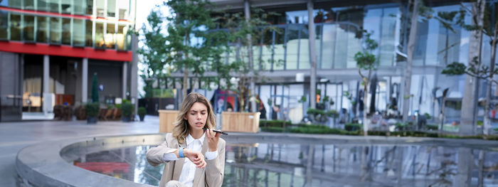 Rear view of woman looking away while standing in city