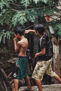 Rear view of shirtless man standing against trees