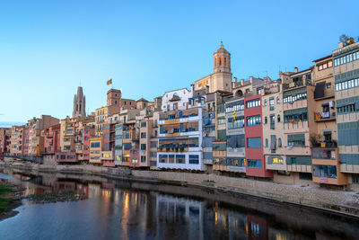 Buildings by river against sky in city