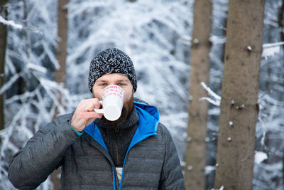 Portrait of man drinking coffee while standing outdoors during winter