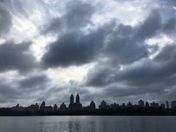 Sea and buildings in city against sky