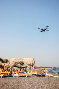 Airplane flying over beach against clear blue sky