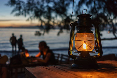 Illuminated old-fashioned lantern on wooden table at shore