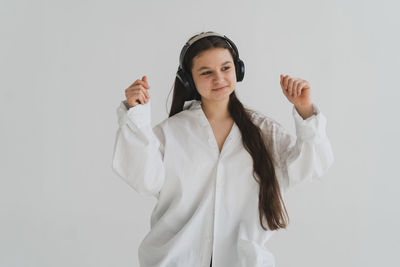 Portrait of young woman standing against white background