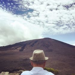 Rear view of man wearing hat standing against mountain