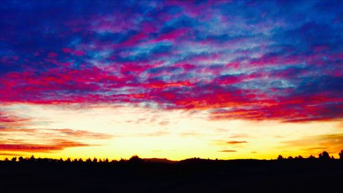 Silhouette landscape against dramatic sky during sunset