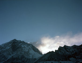 Low angle view of snowcapped mountains against clear blue sky