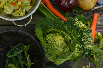 Overhead view of savoy cabbage, celery, carrots, collanders