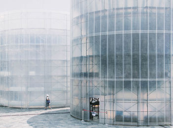 Woman walking by scaffolding buildings on road