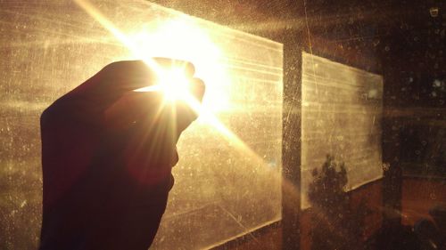 Silhouette man standing by window