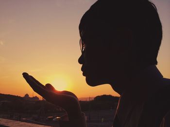 Silhouette of woman against sky at sunset