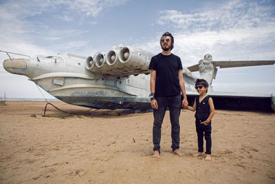 Family a boy and his father in rocker clothes stand ekranoplan plane by the sea in dagestan